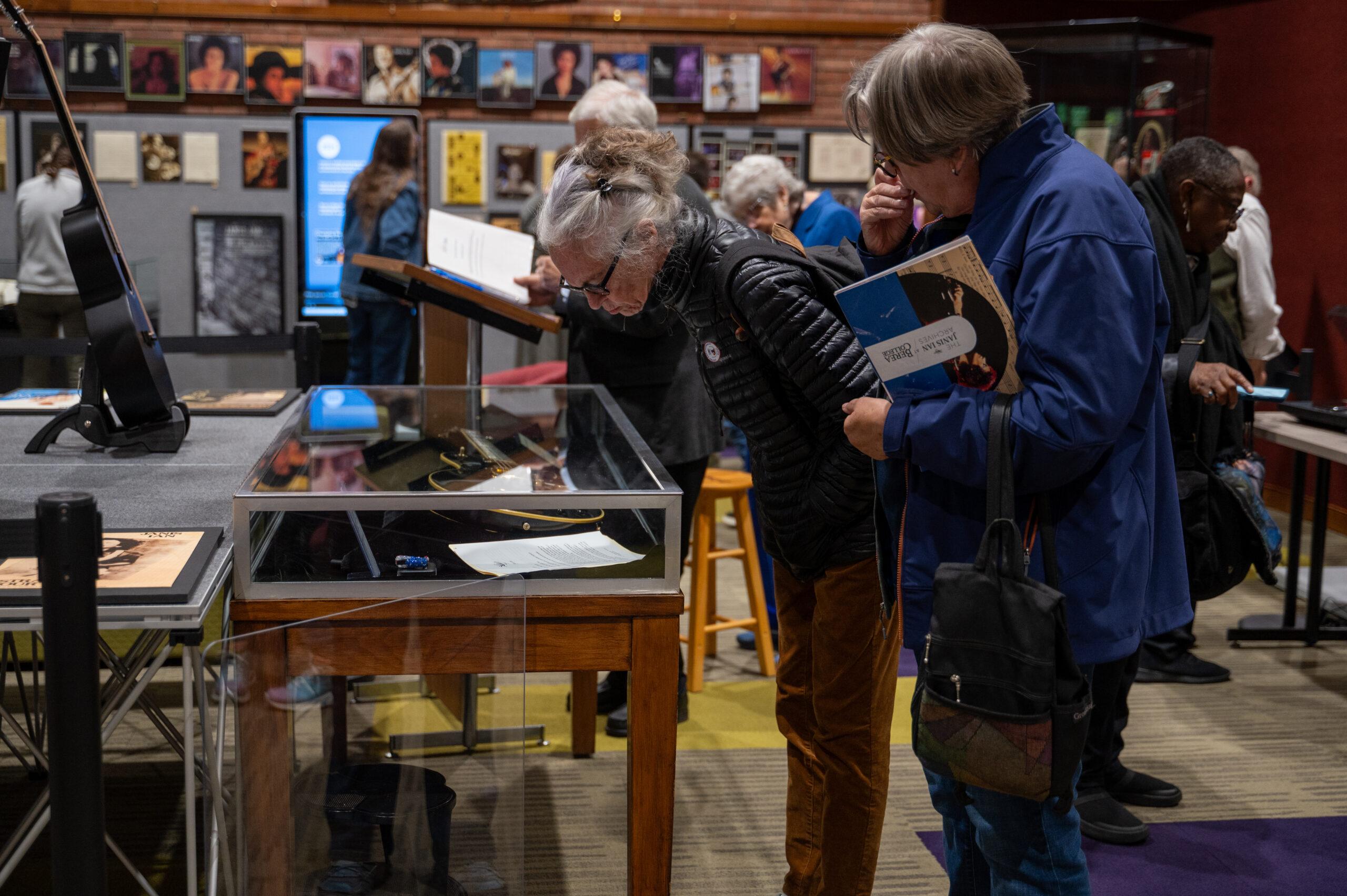 Visitors to Hutchins Library browse the Janis Ian Archives, observing glass displays and curated wall exhibits.